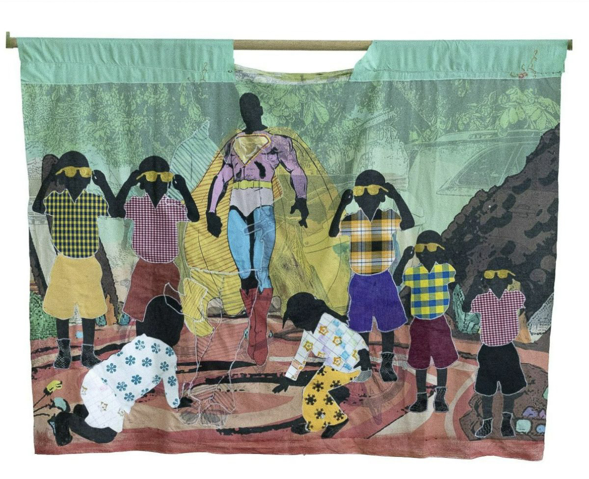 A quilt displaying a group of kids from the PoC community with a superman figure in the middle and printed details showing cars, earthy elements and playing grounds.