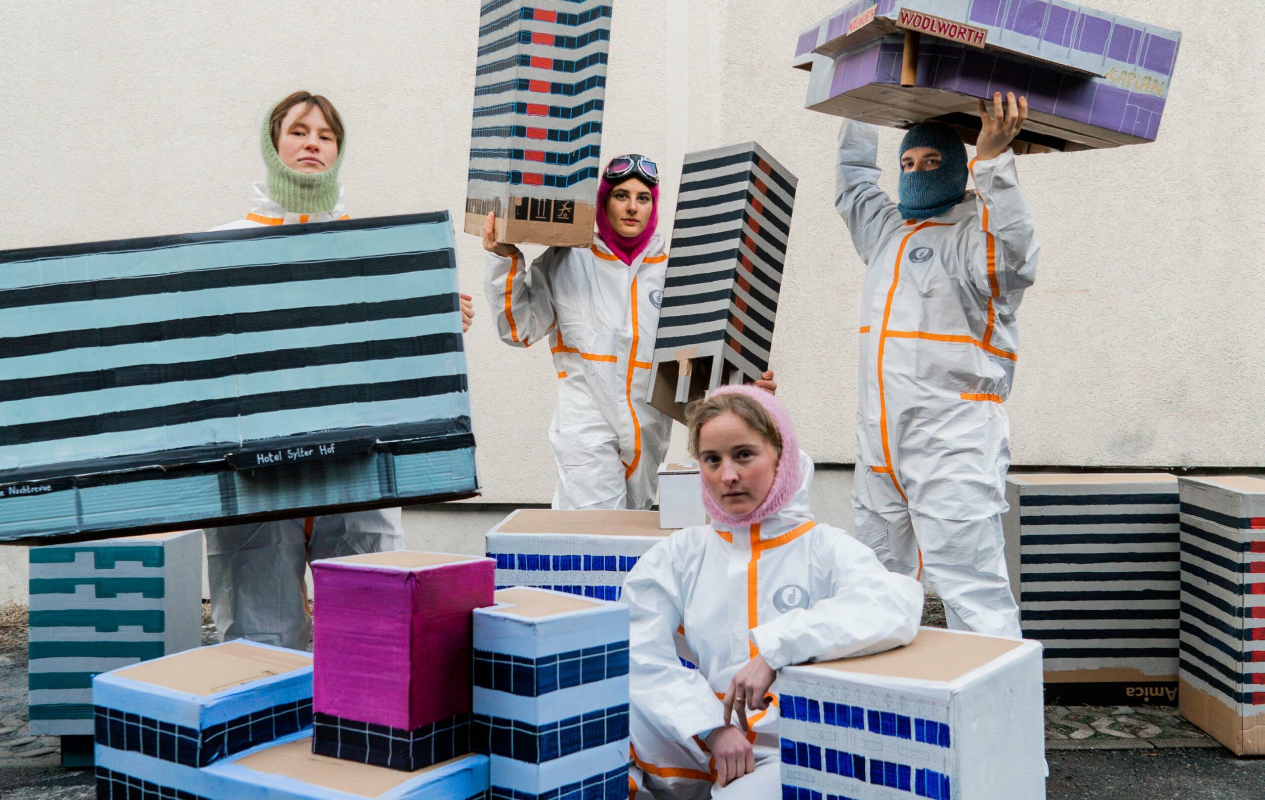 Photo: urban fragment observatory. Lena Löhnert, Florine Schüschke, Jeanne Astrup-Chauvaux and Sebastian Díaz de León (from left to right) with models of the houses threatened with demolition on Kurfürstenstraße and the Urania. All four are holding models of the buildings in front or above their heads.