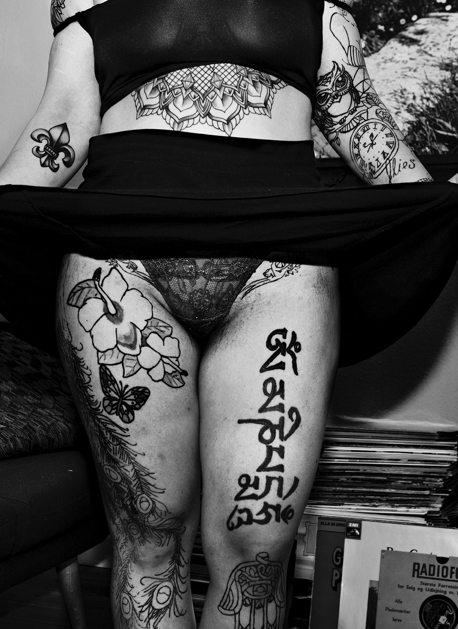 Ein Weiterer Ausschnitt einer Frau, die ihren Rock hebt und damit ihre diversen Tattoos preisgibt.