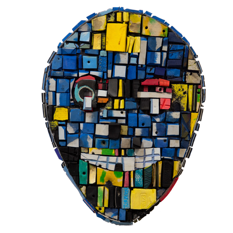 An abstract African mask made out painted wood in blues, yellows and singular reds and greens. 