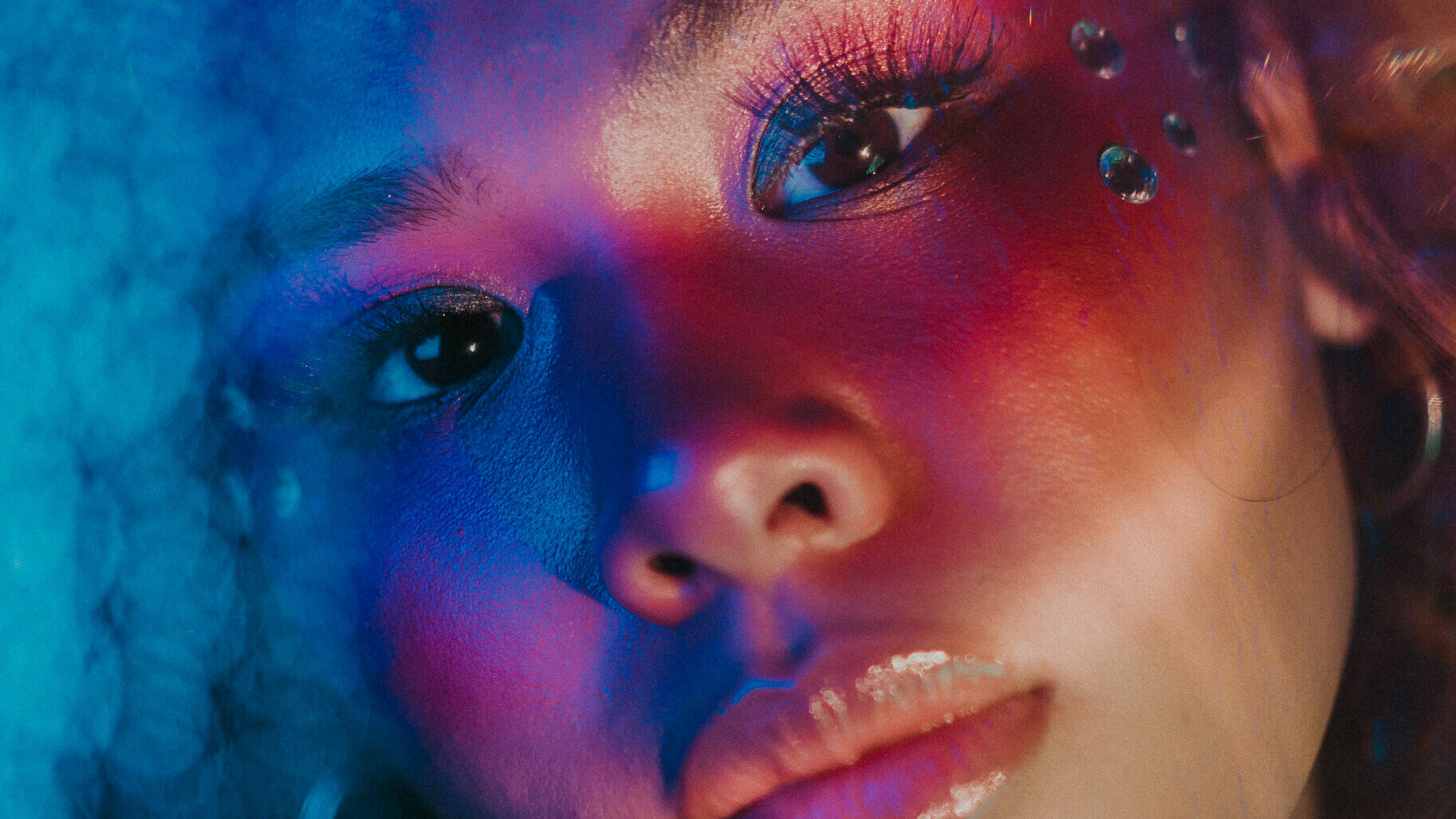 Image of a young BiPoC woman with a colorful make-up and double exposure effect.