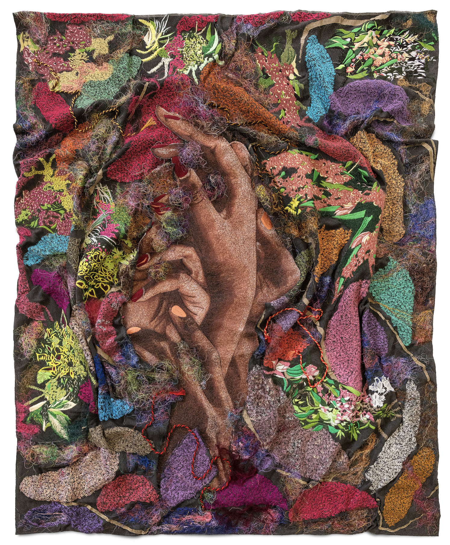 Four hands entangled on an embroidery work and surrounded by bright flowers and colorful patches.