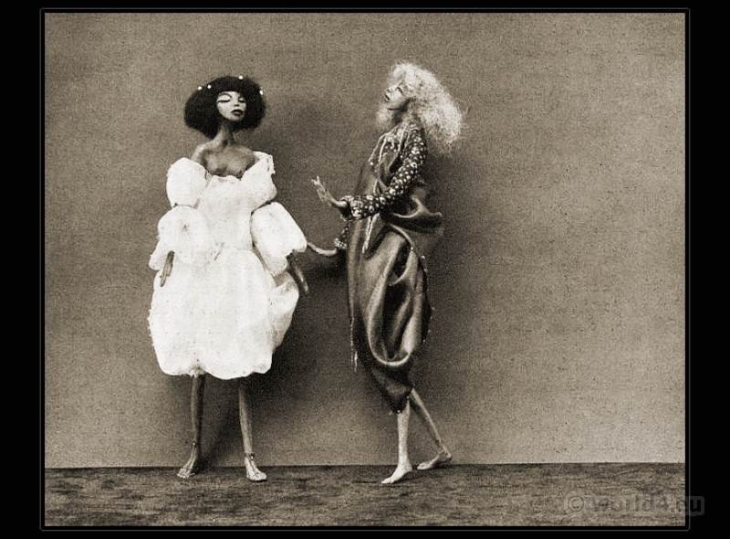 two puppets of women, in black and white, wearing elegant old clothes and apparently talking