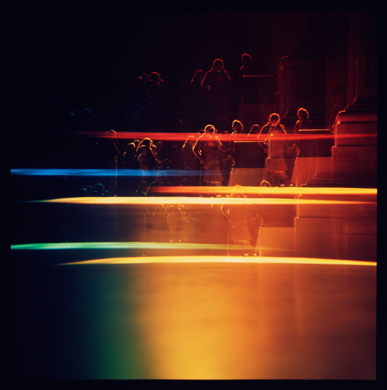 people in the darkness with rainbow like lights